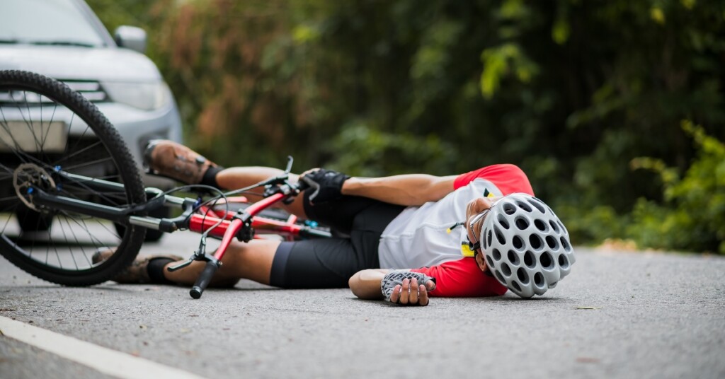 man on ground with bicycle after accident