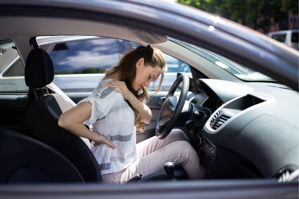 woman holding her back and neck after a car accident