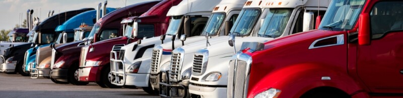 Many semi-trucks side by side in a line.