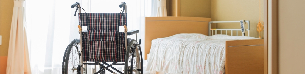 A wheelchair and a hospital bed are alone in a room.