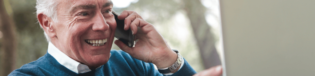 Elderly man using cell phone, and smiling.